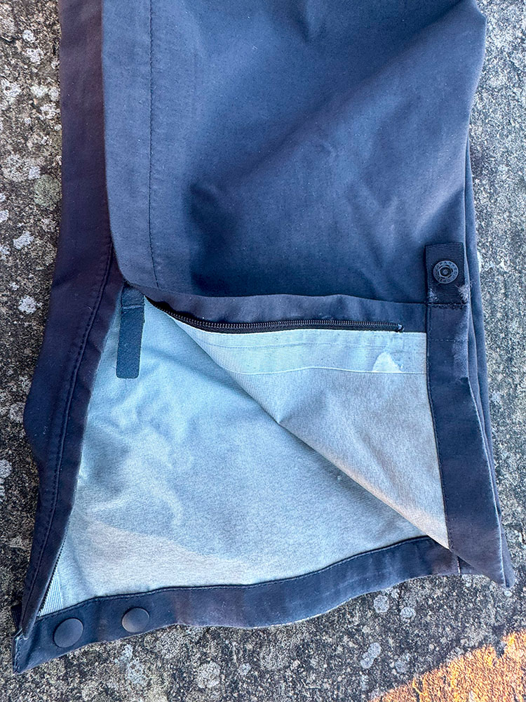 Zip and storm flap on waterproof trousers, with press stud closing around the ankles