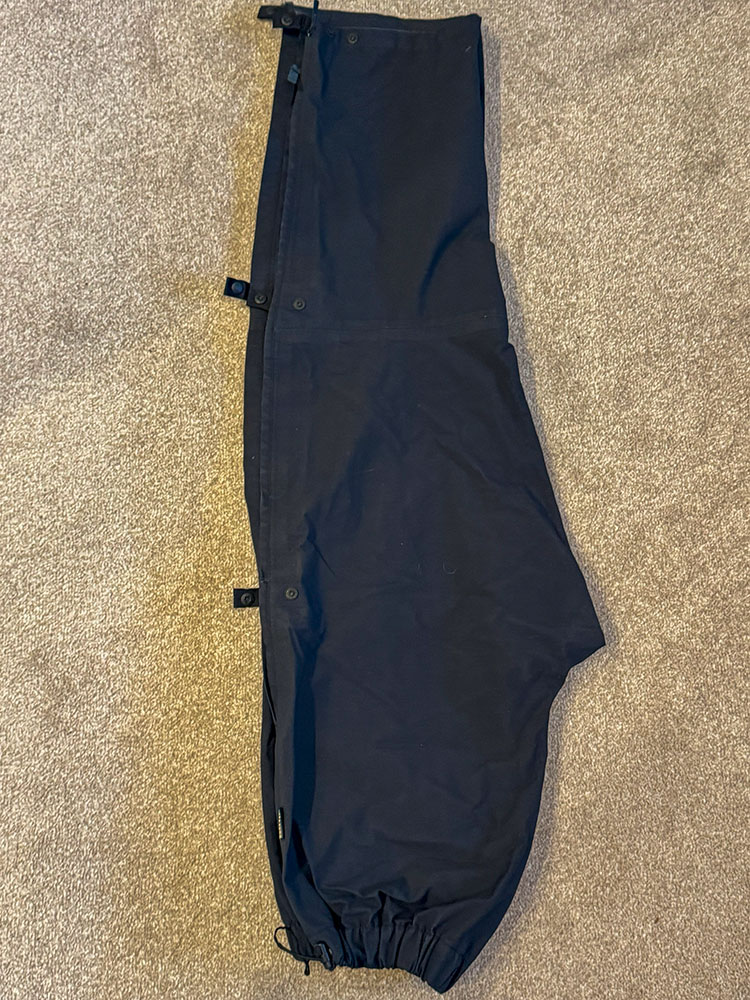 Waterproof trousers folded in half longways with the waist nearest to begin rolling