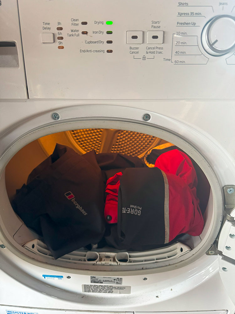 Putting the waterproof jacket and trousers in the tumble dryer, to dry on a gentle heat