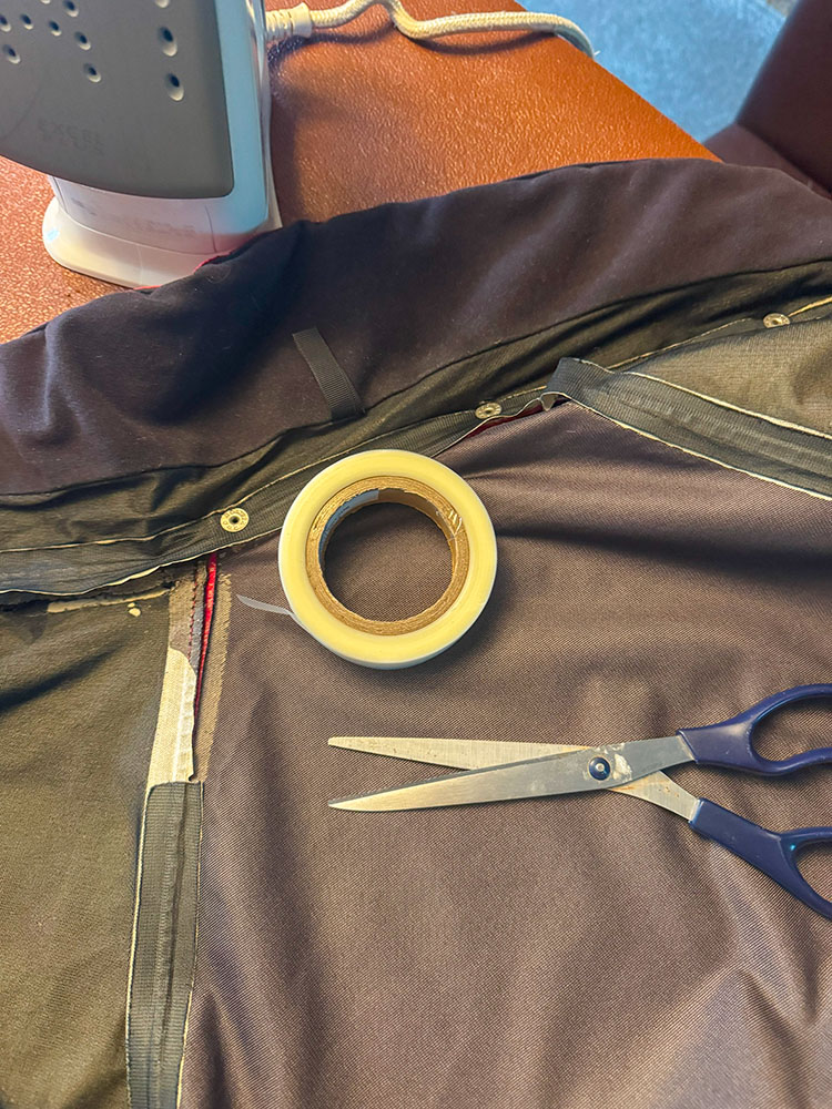 Iron, iron-on tape, scissors ready to repair a seam on a jacket