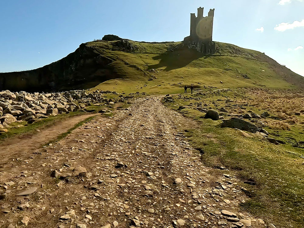 Following the footpath around the base to the right of Dunstanburgh Castle