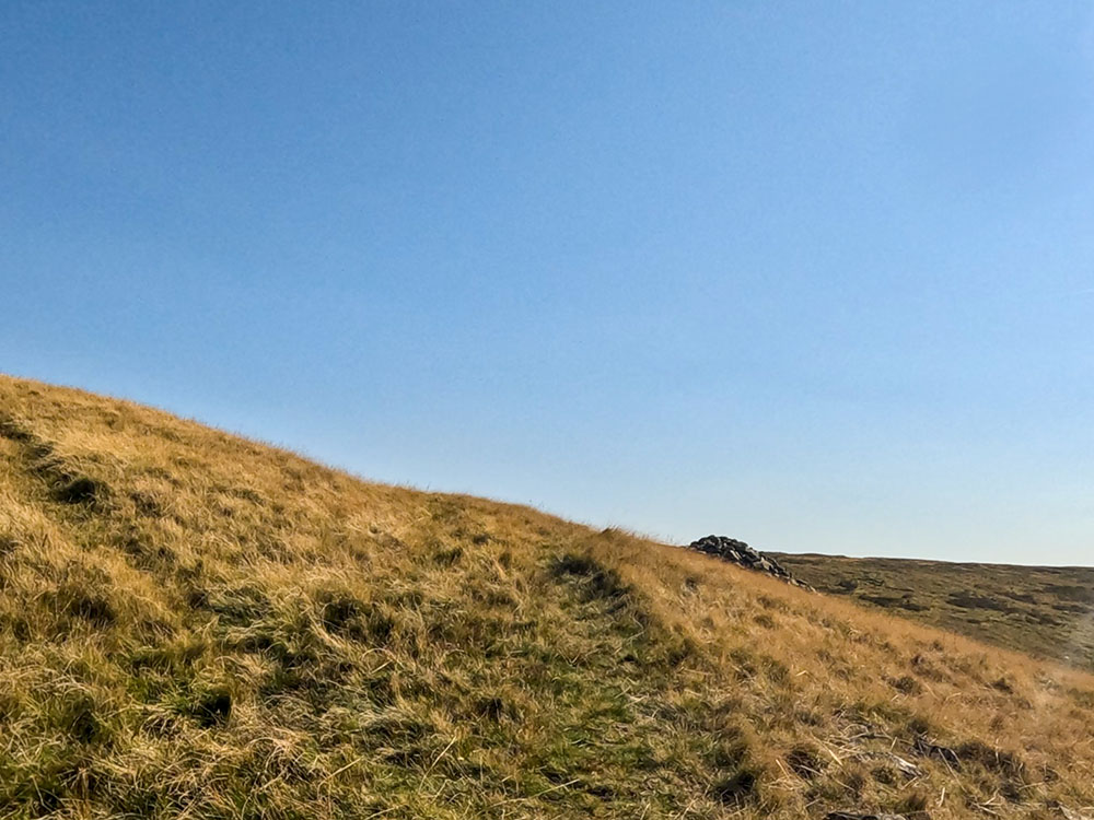 As a cairn becomes visible ahead, leave that path and turn left to head steeper uphill