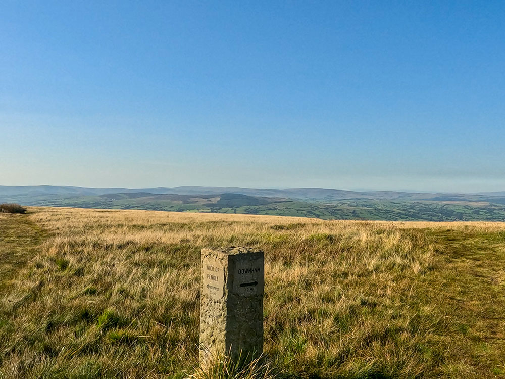 Just on the far side of the wall, follow the Downham sign on the stone marker post