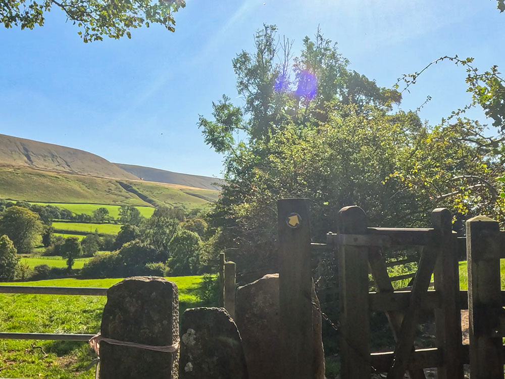 Follow the yellow arrow on the gate stile. Ahead is the part of Pendle Hill being climbed on this walk.