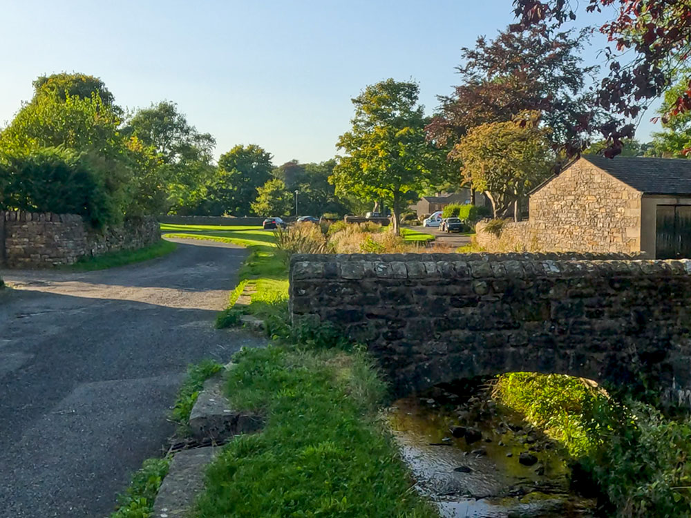 Pass by a stone bridge over Downham Beck before turning right along Pendle Road