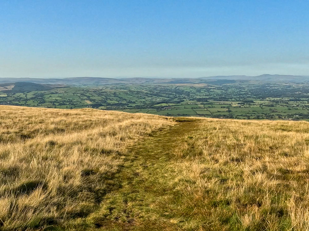 The grassy path heads away from the wall, descending gently at first