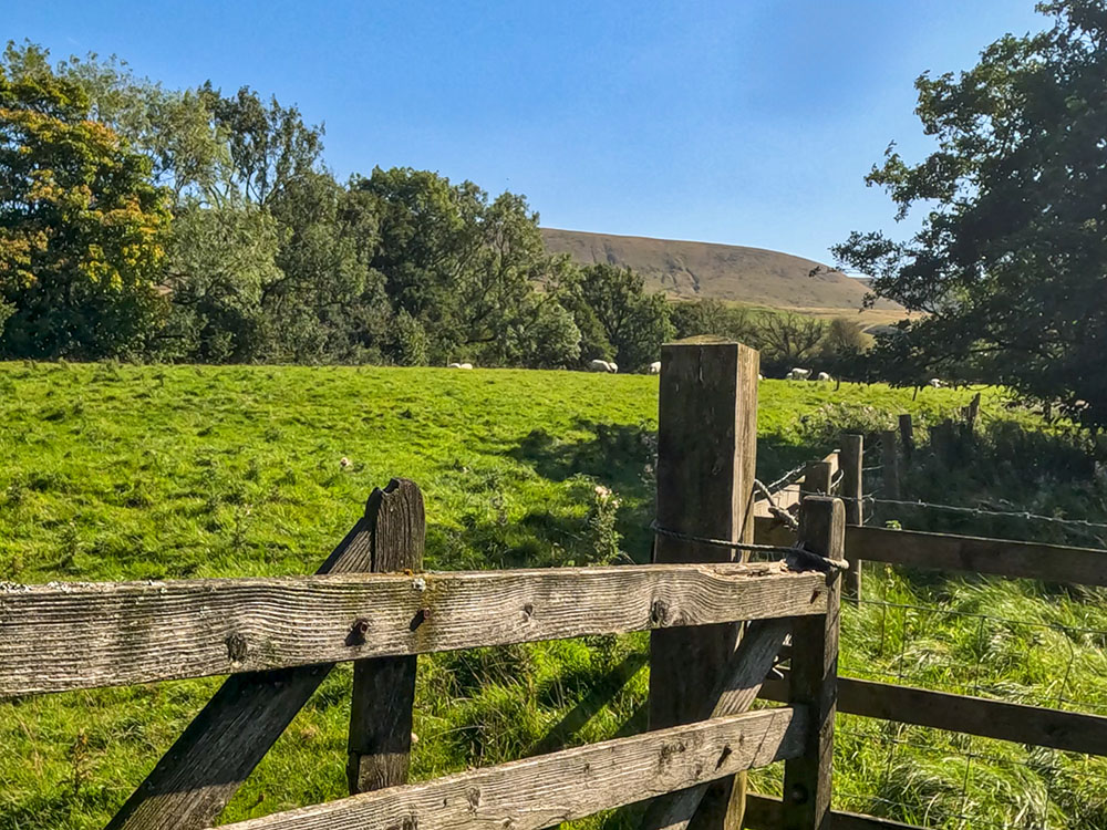 The path heads through a wooden gate and then across to the far corner of the field