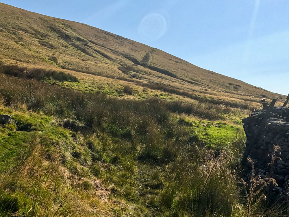 As the wall bends around to the right, the path also heads around to the right. The path up the hill can be seen ahead