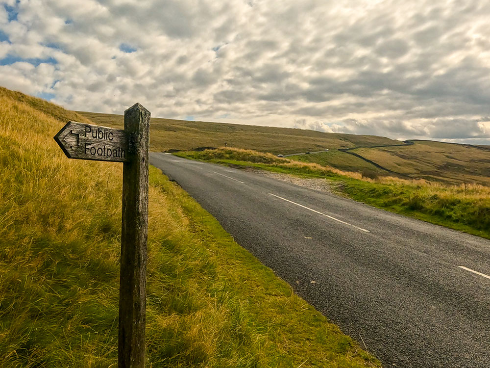 The path drops down onto Clitheroe Road by a public footpath sign. We head up the road the short distance to the ski slope and the Wellsprings.